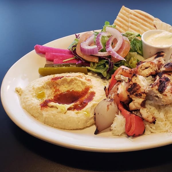 Sam's Pita and Kabab chicken kabob plate with hummus, rice, salad, pita, and pickles.