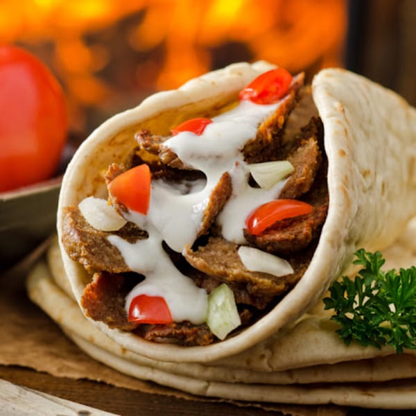 Sam's Pita and Kabab's gyro, filled with meat, tomatoes, onions, and white sauce, on a pita.